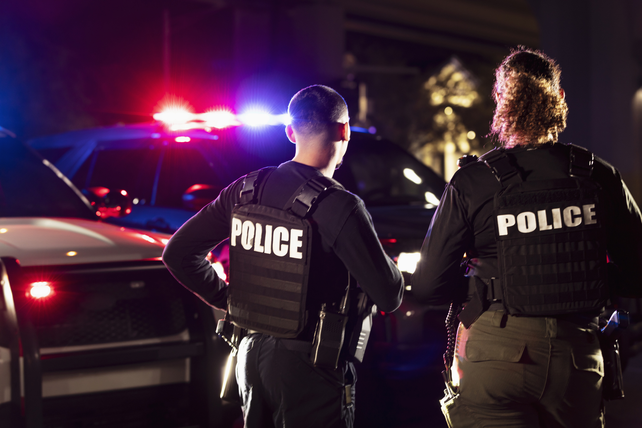 Two police officers standing outside at night.
