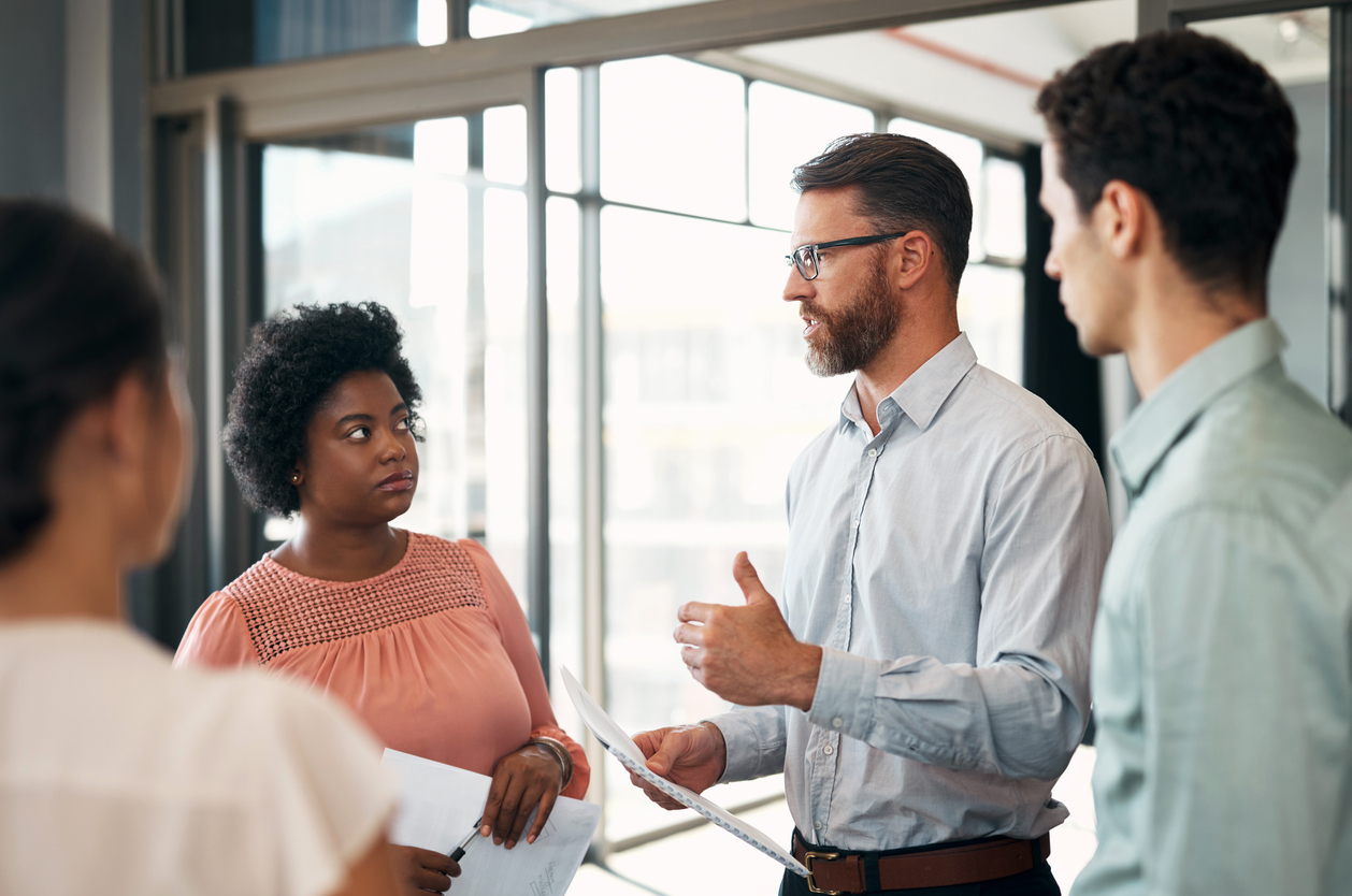 Training and development specialist in an office setting talking with employees.