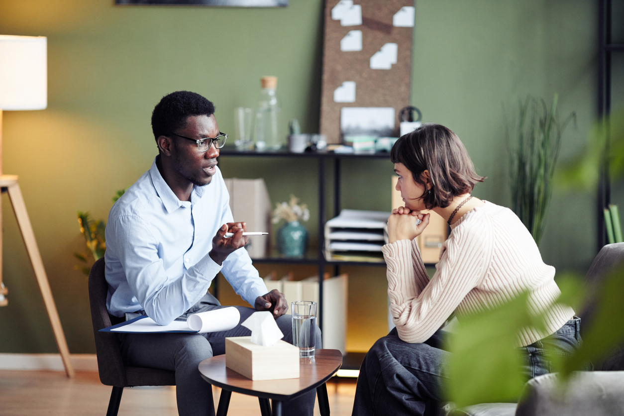 Psychologist sitting with a client in an office and talking with her.