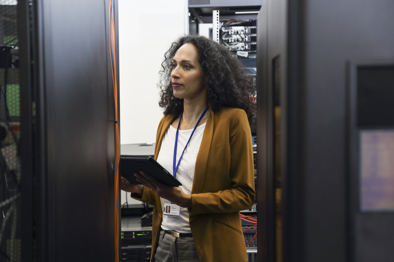 A cybersecurity professional with a tablet in a control room. 