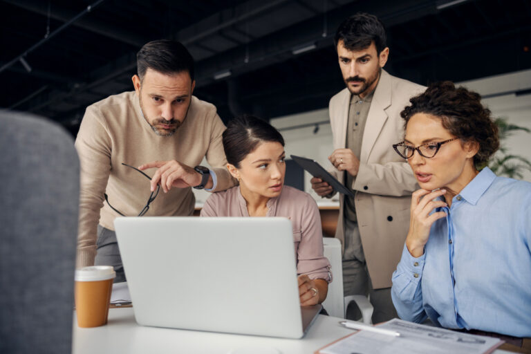 A crisis team meets in front of a laptop.